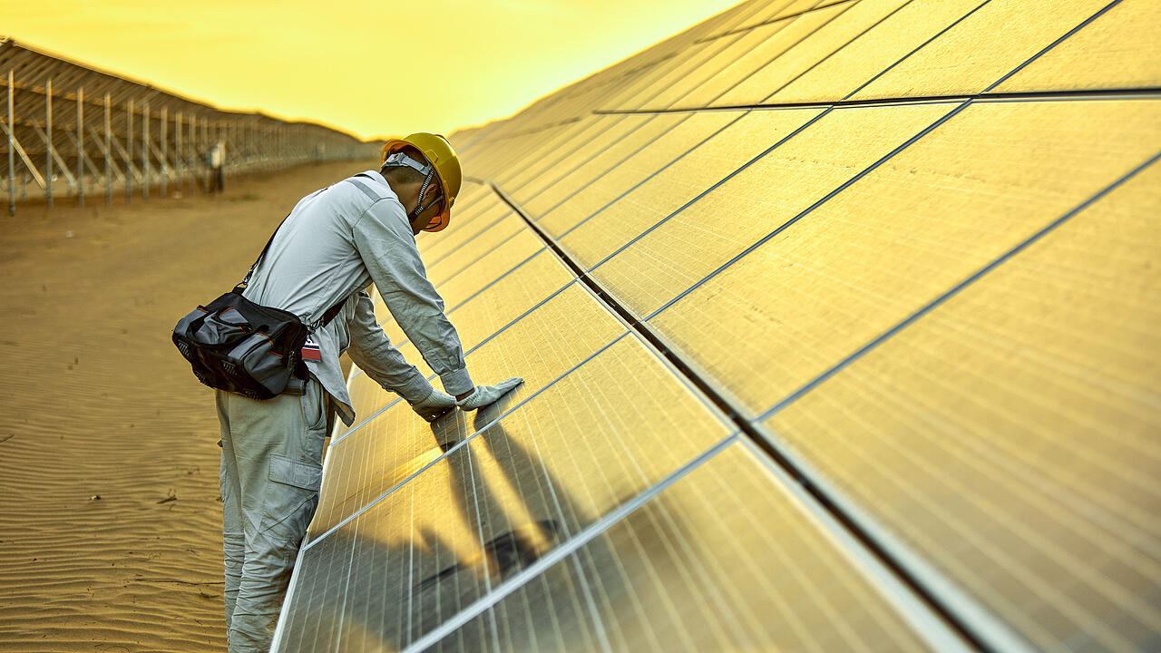 Un ingénieur teste un système photovoltaïque dans le désert, avec un ciel jaune en toile de fond