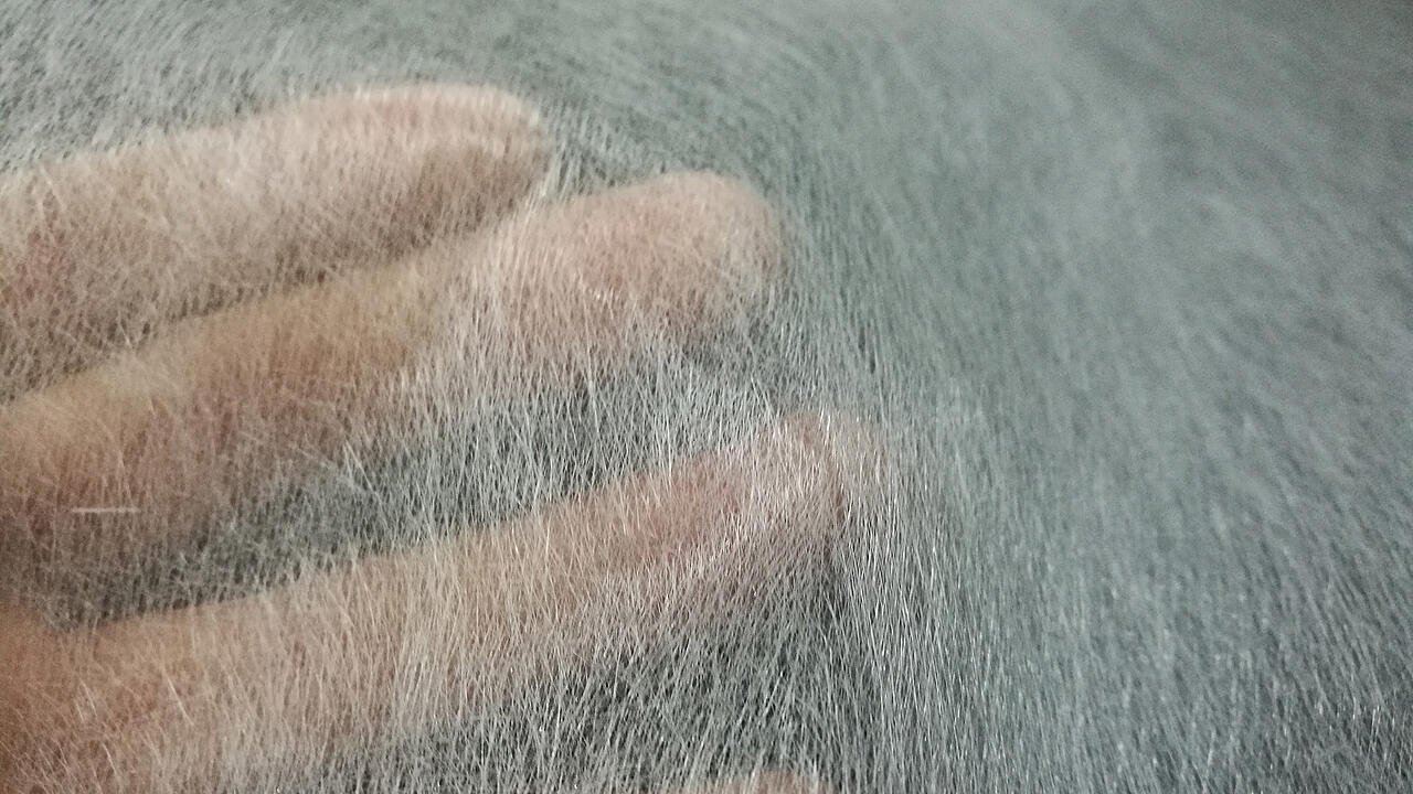 Mano ligeramente borrosa detrás de un tejido de fibra de vidrio