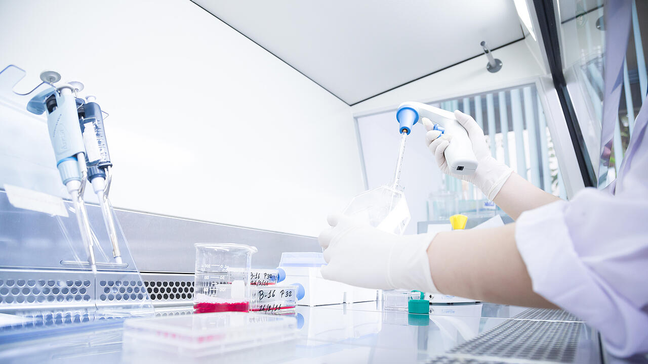 Científicos en la sala limpia (caja de guantes) realizando el llenado con pipetas
