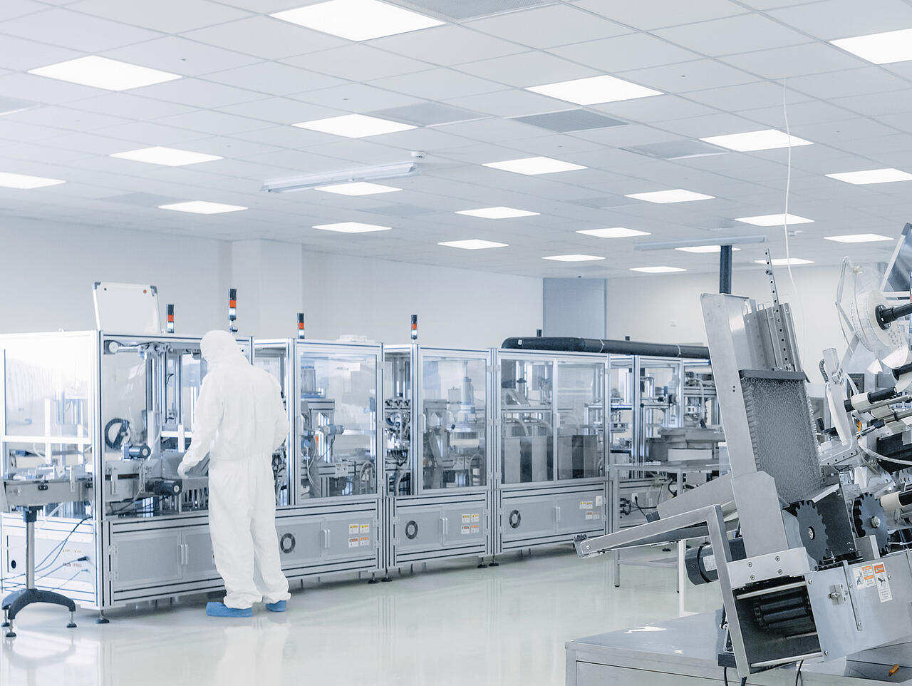 Nave de producción dedicada a la investigación en semiconductores, con científicos equipados con material de protección junto a las máquinas