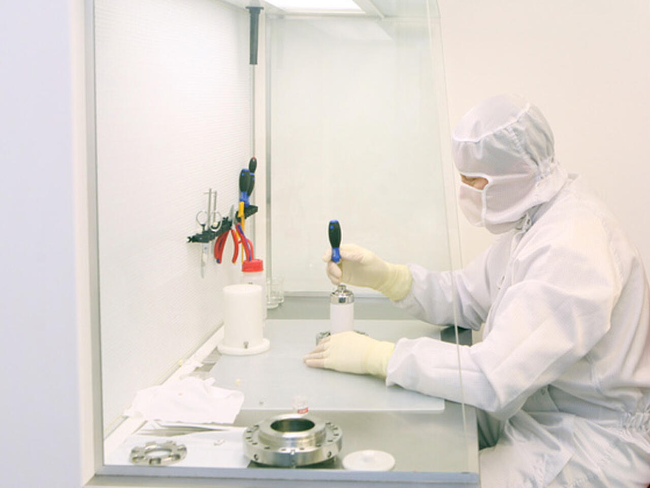 Mesa de trabajo de seguridad, con un técnico de laboratorio delante, vestido con un traje de protección, trabajando con una muestra