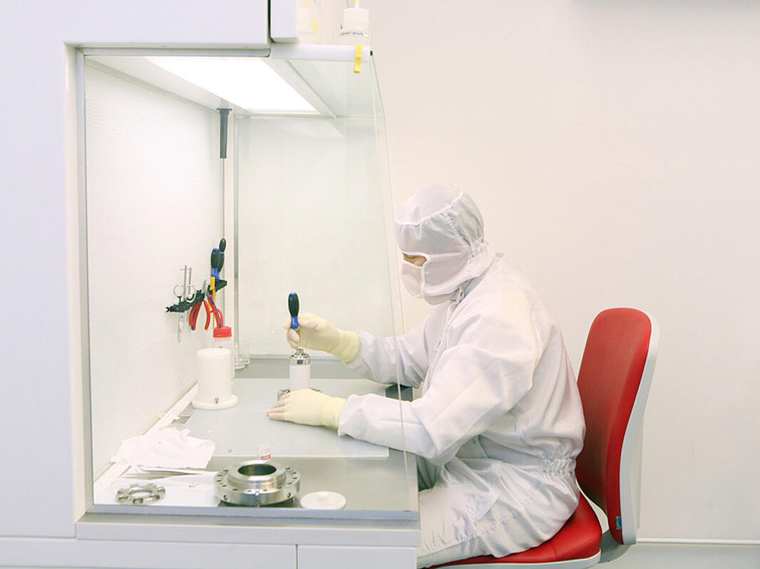 Cabina de seguridad con un técnico de laboratorio delante, vestido con un traje de protección, que trabaja con una muestra