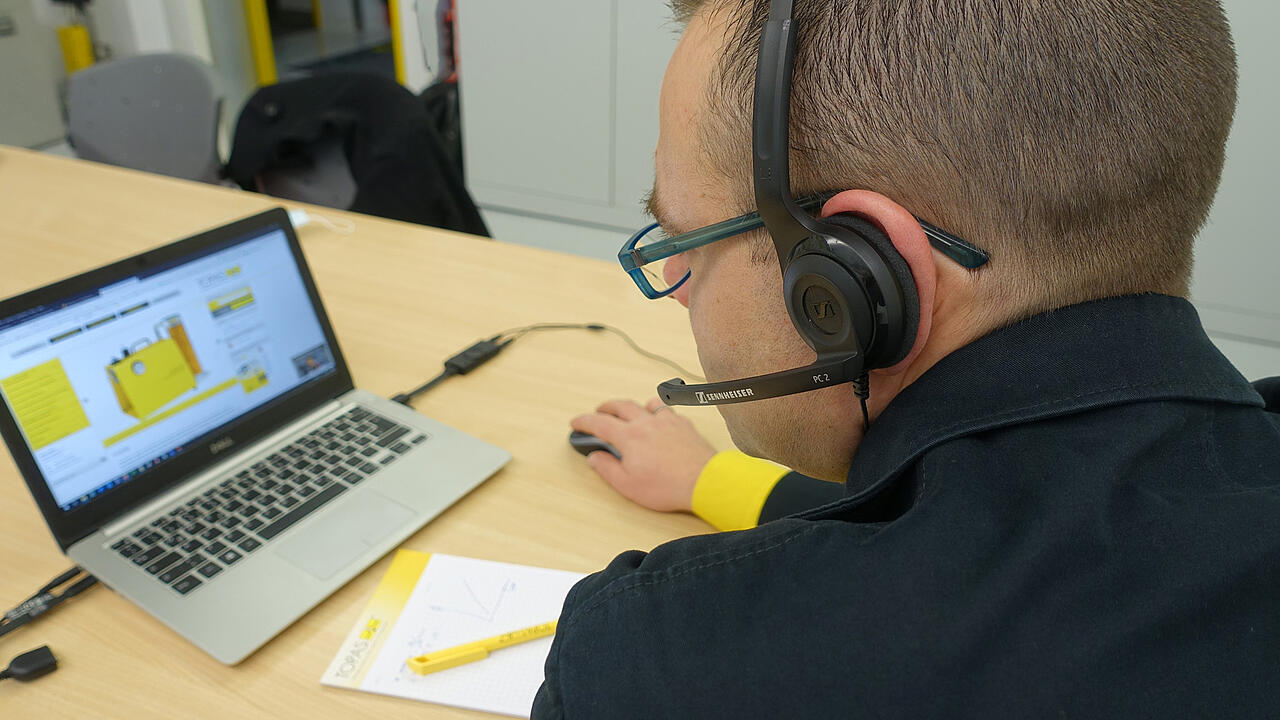 Empleados con auriculares, ordenador portátil y material de escritura en la mesa