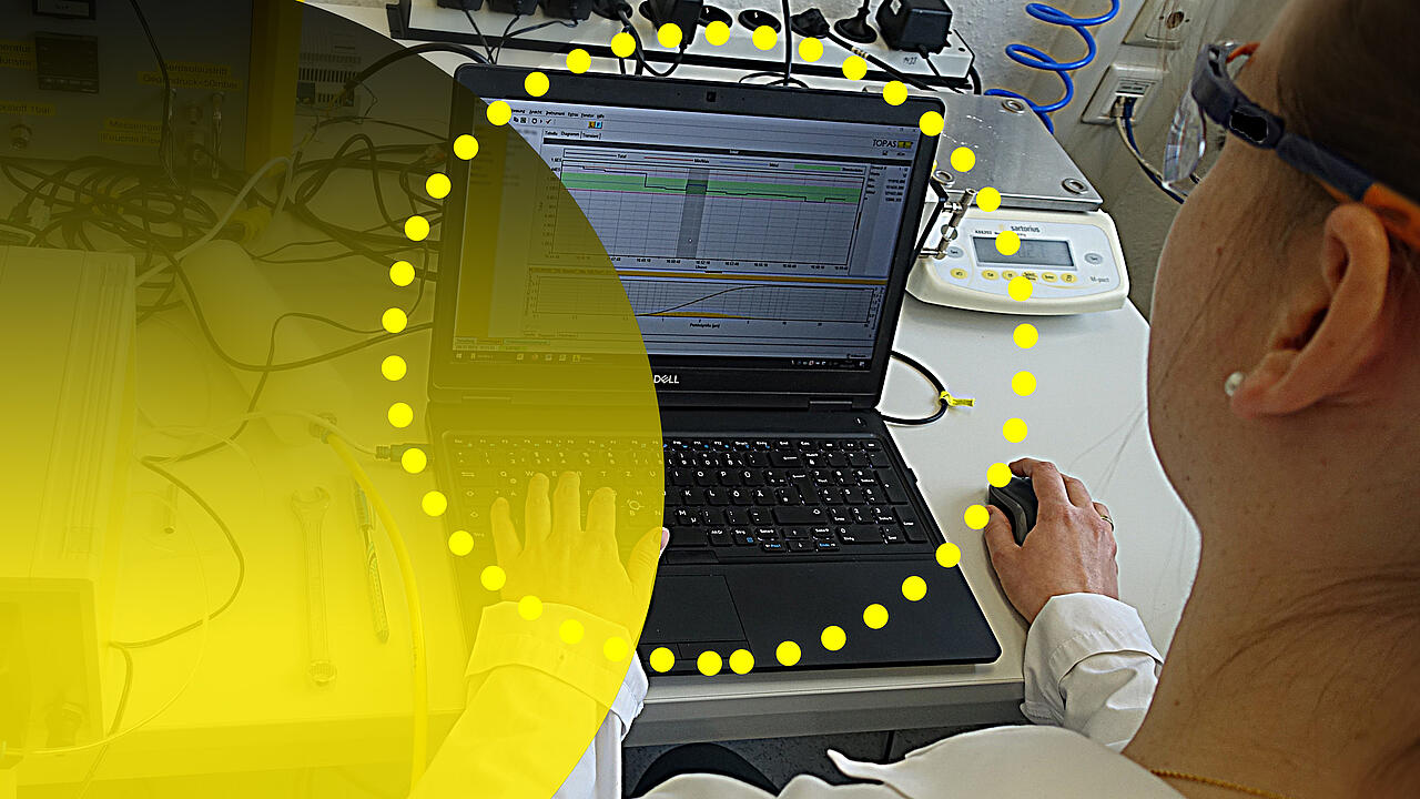 Laboratorio de investigación: una persona frente al ordenador, vista por encima del hombro, con círculos amarillos en primer plano