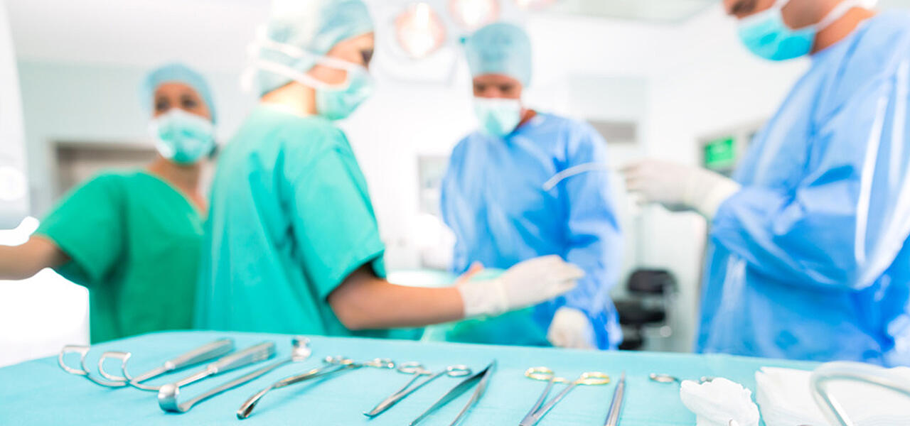 Médicos y enfermeros junto a la mesa de operaciones, que se ve en primer plano con numerosos instrumentos sobre ella