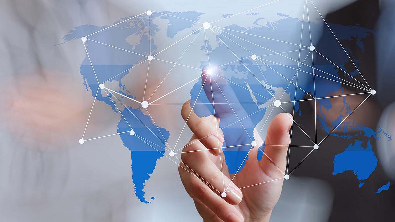 Mapa del mundo sobre cristal, con una persona de pie al fondo